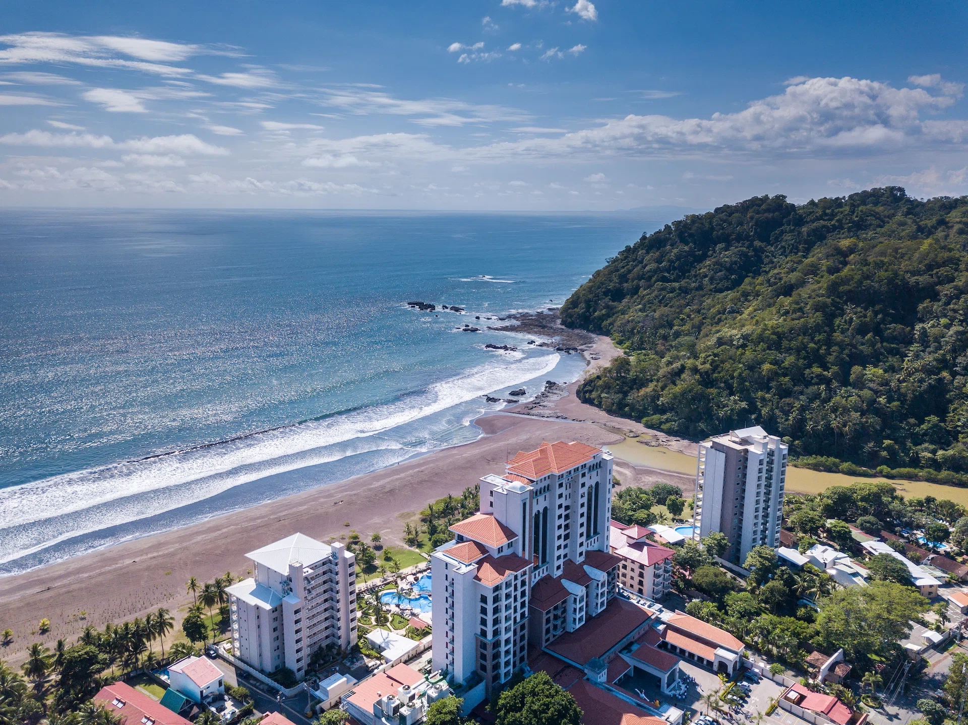 Vista aérea de Playa Jacó, Costa Rica — el país desde donde trabajamos, en tu zona horaria.